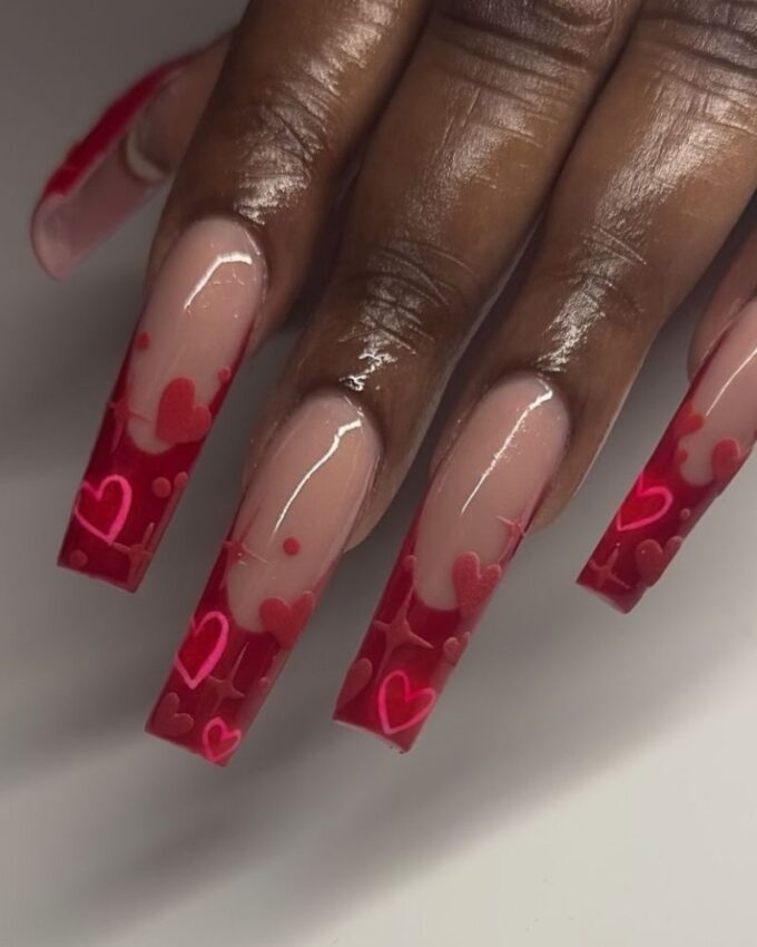 Manucure stilettos rouges avec des accents roses et des motifs 3D