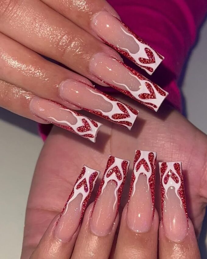 Ongles longs avec pointes rouges scintillantes et un effet cœur enflammé