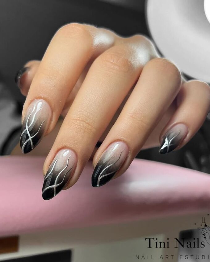 Ongles stilettos avec des pointes ombrées noires et des lignes argentées