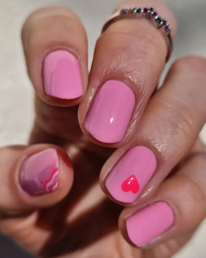 Ongles courts avec une base rose et des motifs colorés